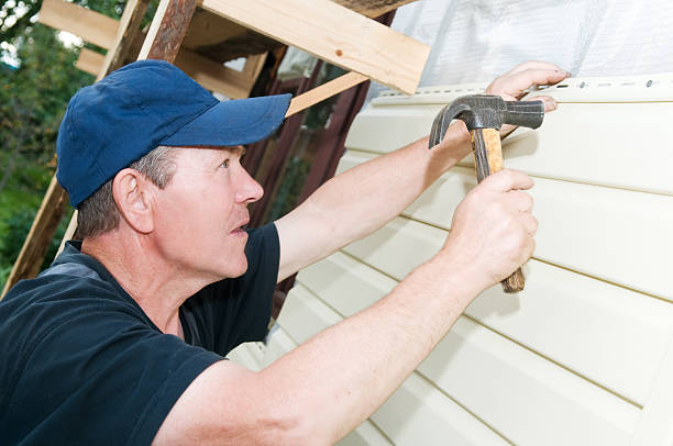 Installer securing vinyl siding panel to home exterior with hammer