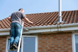 Worker repairing gutters on the roof as part of exterior building services
