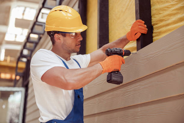Worker installs exterior siding panels on residential wall frame