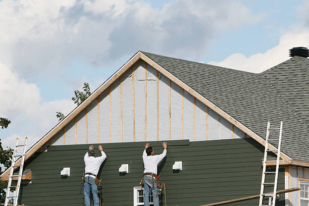 Crew installing green siding on upper wall of residential home