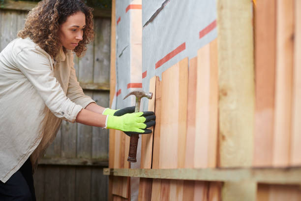 Worker carefully installing cedar wood siding on a house's exterior