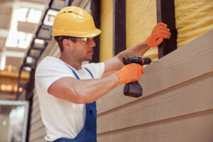 Worker installing James Hardie fiber cement siding with power drill