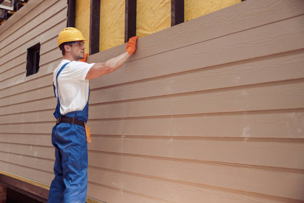 Construction worker installing engineered wood siding on house exterior