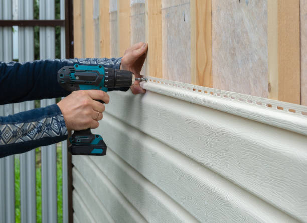 Worker using drill to install horizontal house siding on wood frame