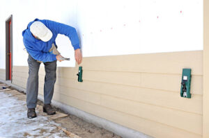 Contractor installing engineered wood siding panels on house wall