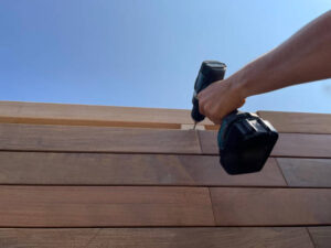 Installing wood siding on a house with a drill and wooden panels
