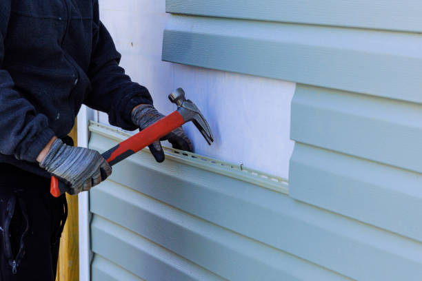 Contractor installing vinyl siding using hammer on house exterior