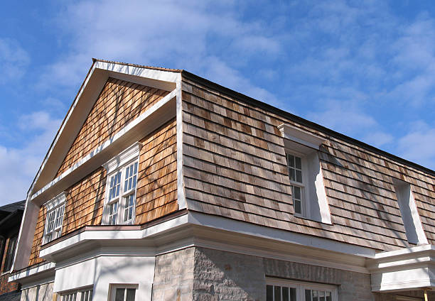 Newly installed cedar siding on a residential home with a clear sky