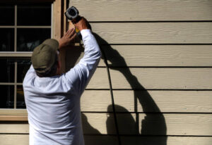 Worker installing James Hardie fiber cement siding around window