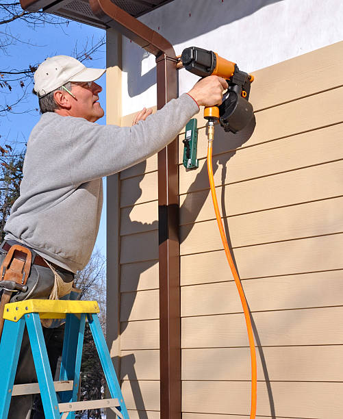 Worker applying James Hardie fiber cement siding using a power drill
