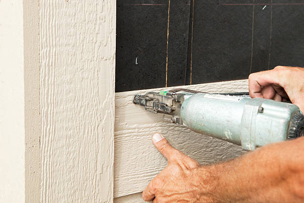 Close-up of a worker installing fiber cement siding using a nail gun